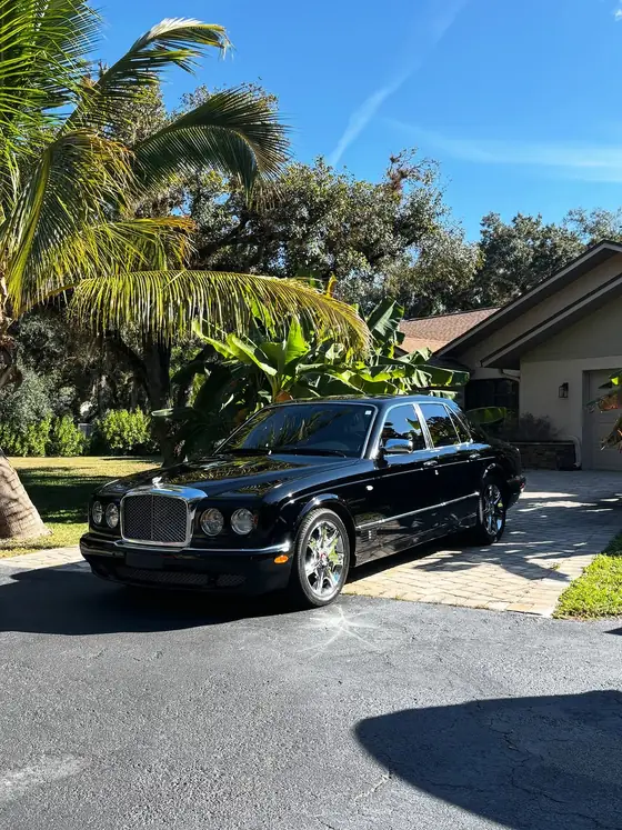 Black Bentley Arnage gleaming in a driveway surrounded by tropical plants