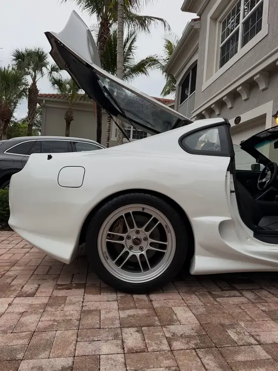 Rear quarter of a white Mk4 Supra with hatch open, paint gleaming
