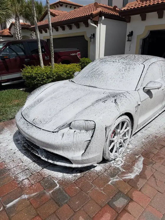 Porsche Taycan covered in thick snow foam during a wash