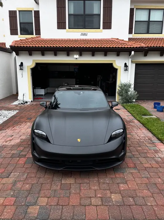 Matte black Porsche Taycan parked on brick pavers after a detail