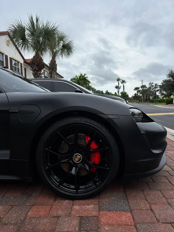 Gloss black Porsche wheel with red brake caliper, spotless after detail